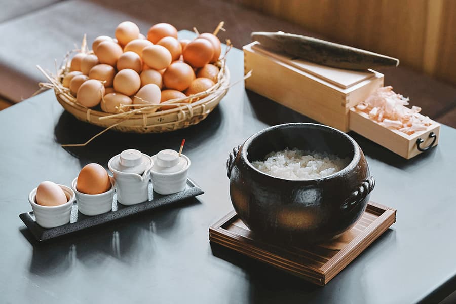 炊き立てごはんの入った土鍋と、かごに盛られた朝採れ卵、本枯鰹の削り箱が並ぶ朝食の設え