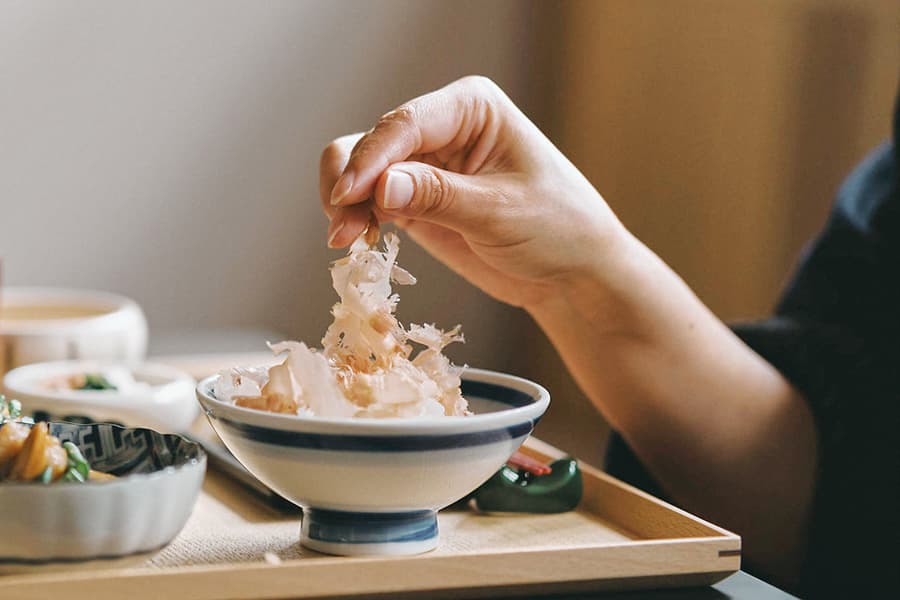 ごはんの上に削りたての本枯鰹をふわりとのせる手元