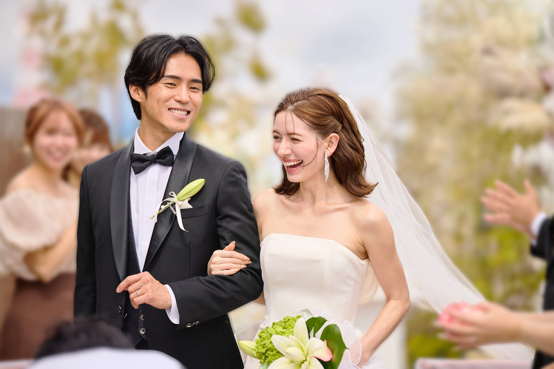 祝福の拍手とフラワーシャワーの中を歩く新郎新婦