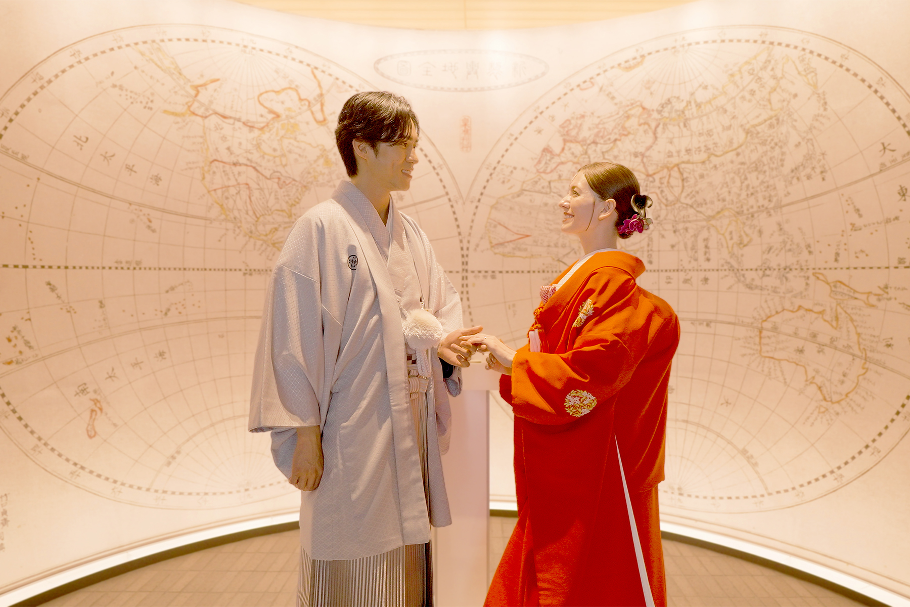 世界地図を背景に向き合う和装の新郎新婦、エントランス